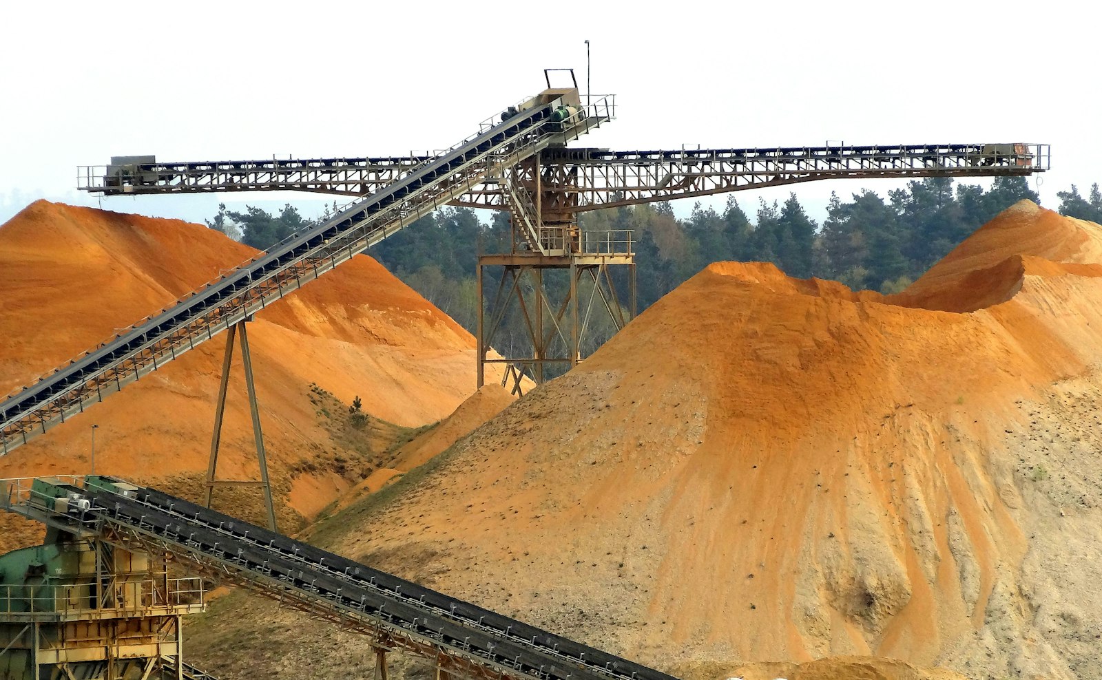Conveyor systems carrying material over large stockpiles at a processing site.