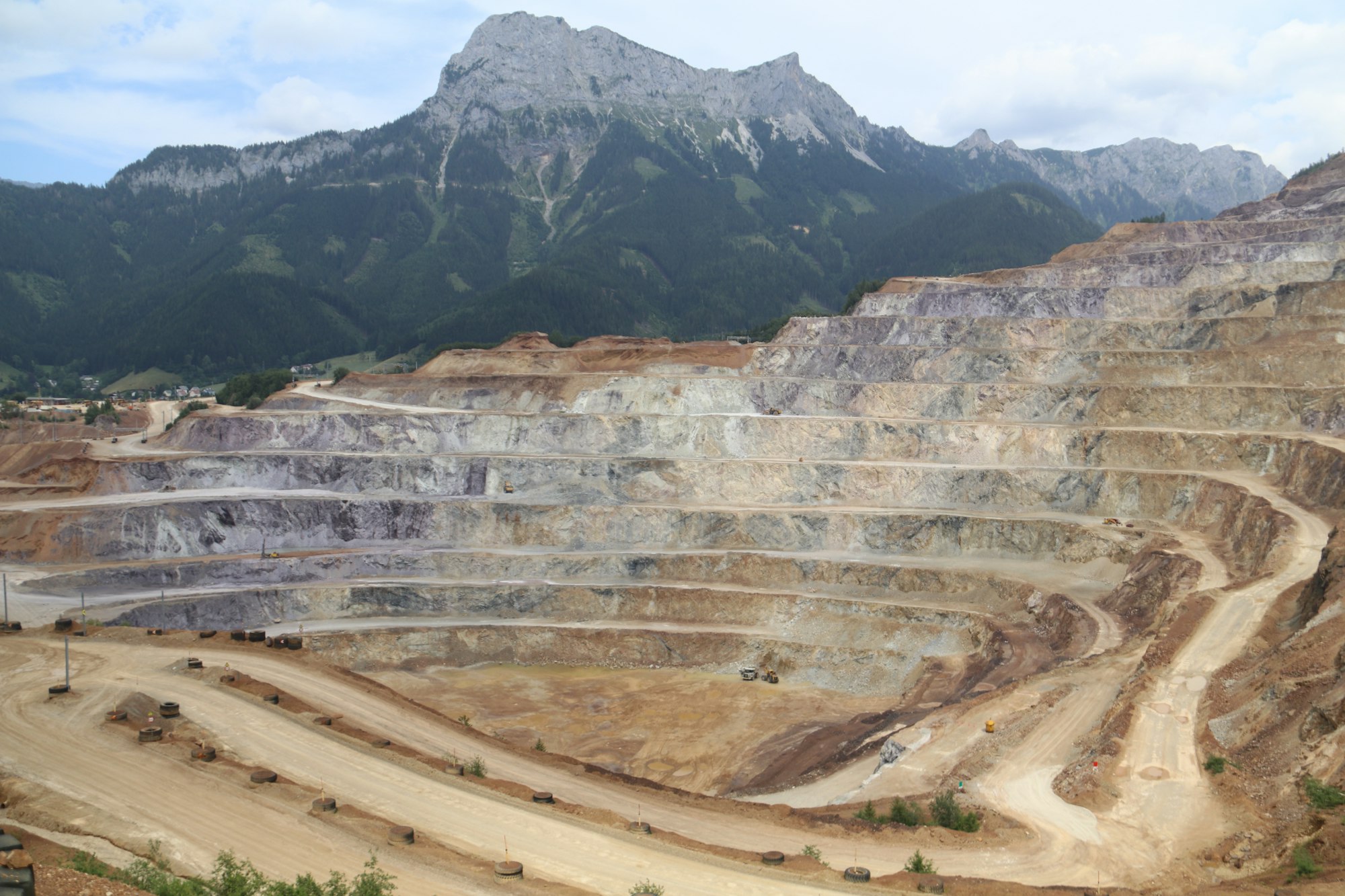 A terraced open-pit mine set against mountains.