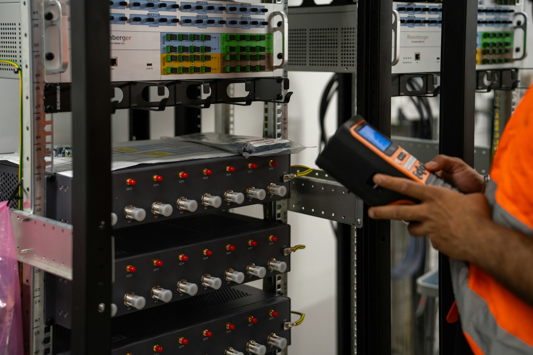 A technician inspecting server racks with a handheld diagnostic tool.