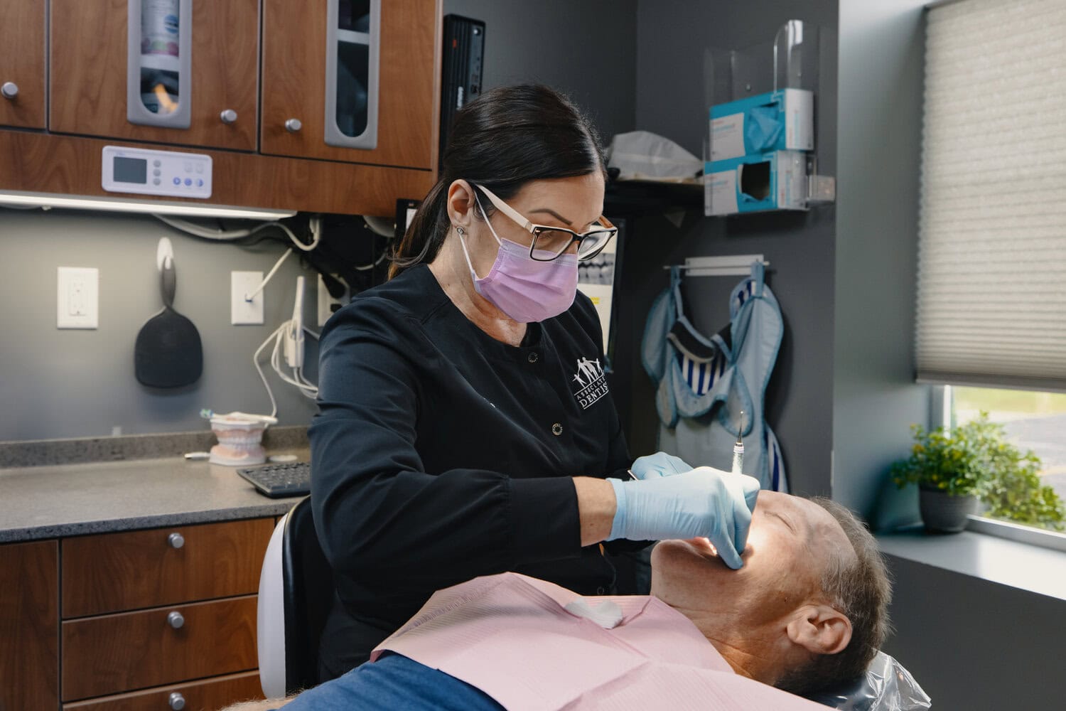 Hygienist in a mask cleaning a patient's teeth in a dental chair