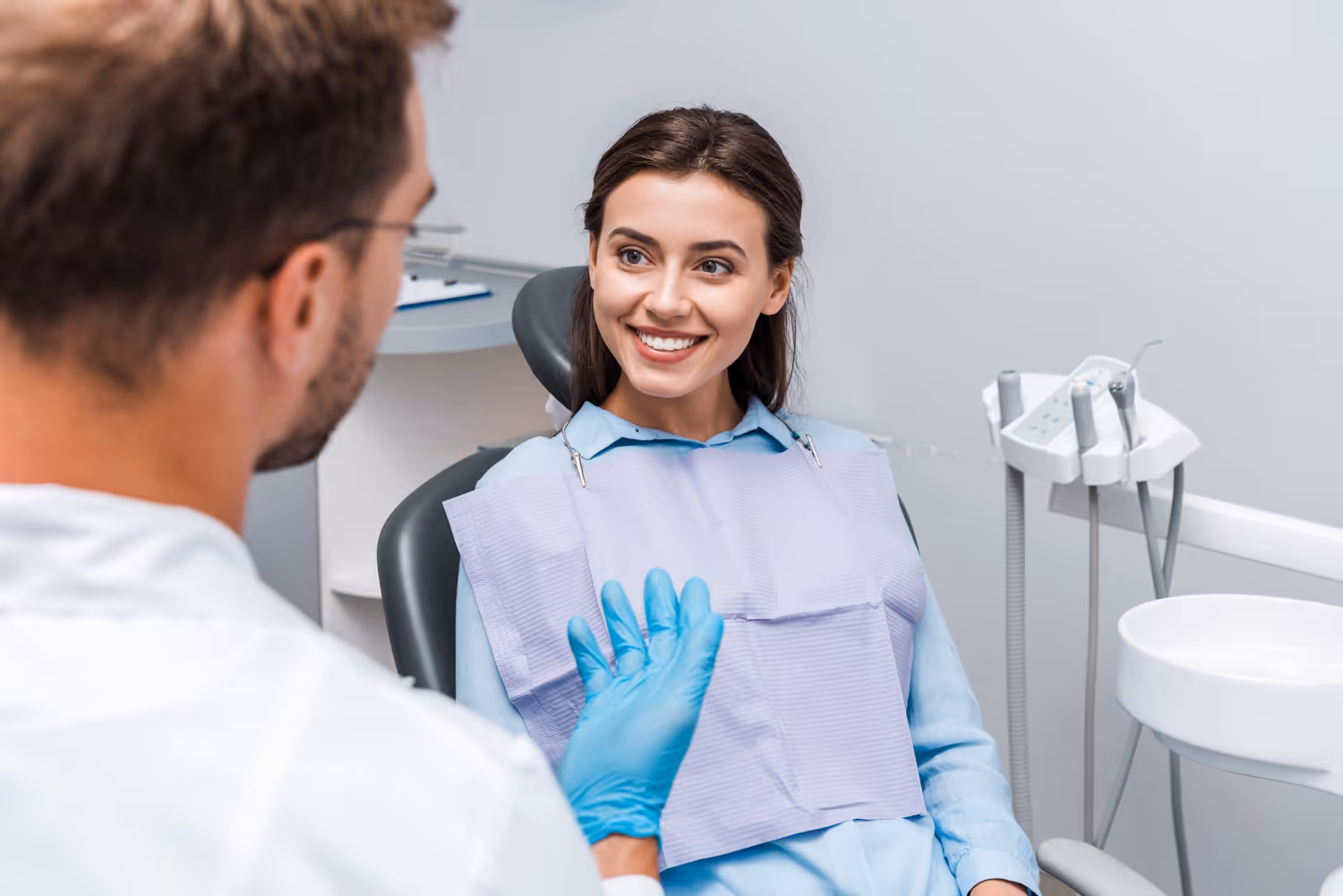 Smiling patient in a dental chair talking with her dentist