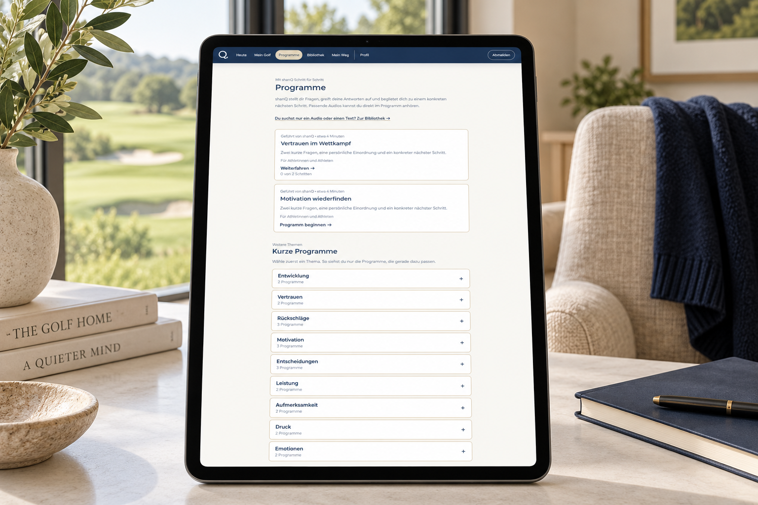 Tablet mit der shanQ Programmübersicht auf einem Tisch mit Blick auf den Golfplatz.