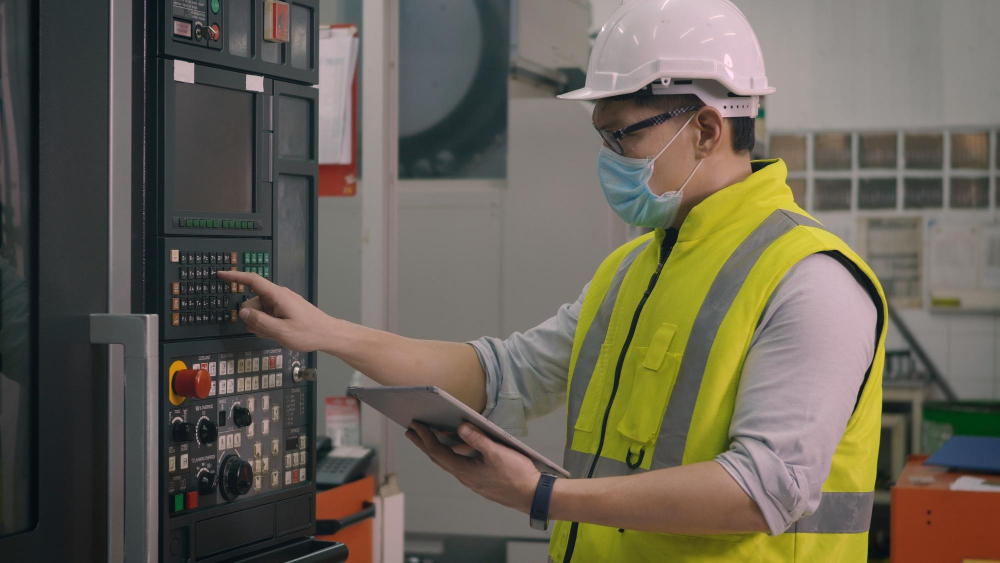 A young technician in a hard hat checking equipment