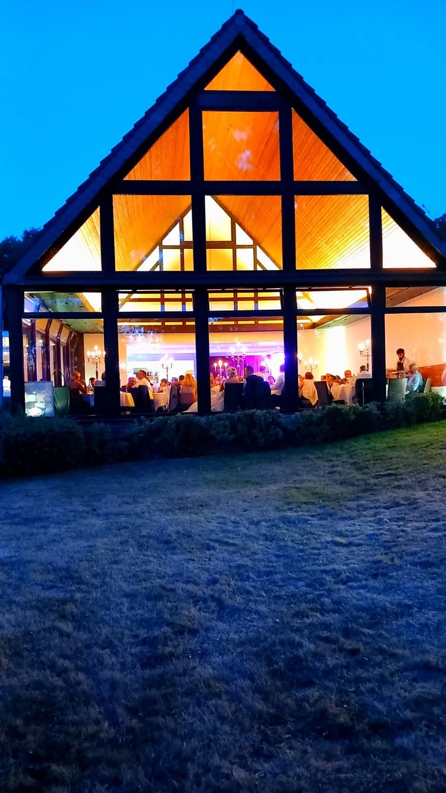 Wintergarten mit runden, eingedeckten Tischen und großen Fenstern zum See