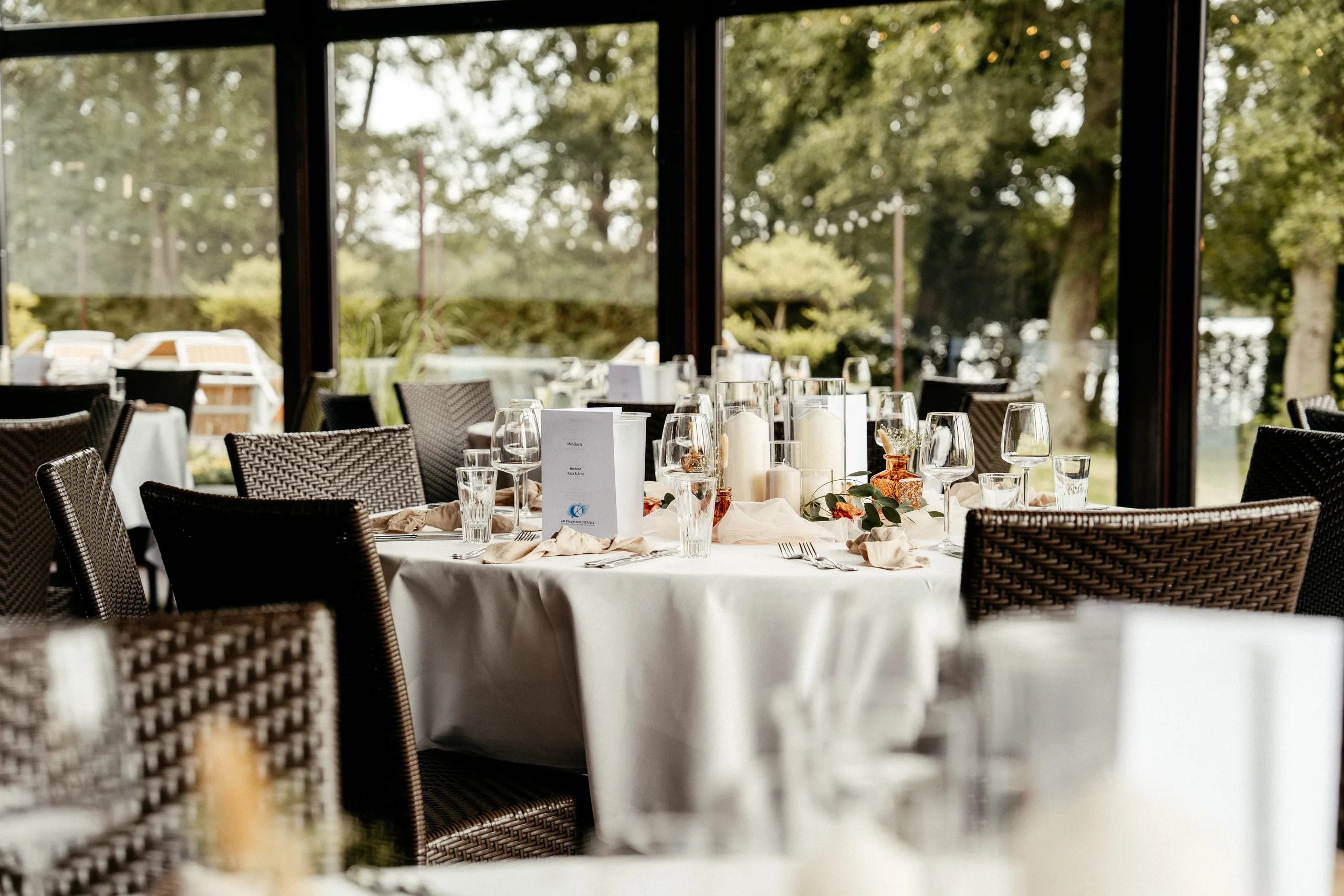 Eingedeckter Tisch mit Wiesenblumen, im Hintergrund Fenster mit Blick auf den See