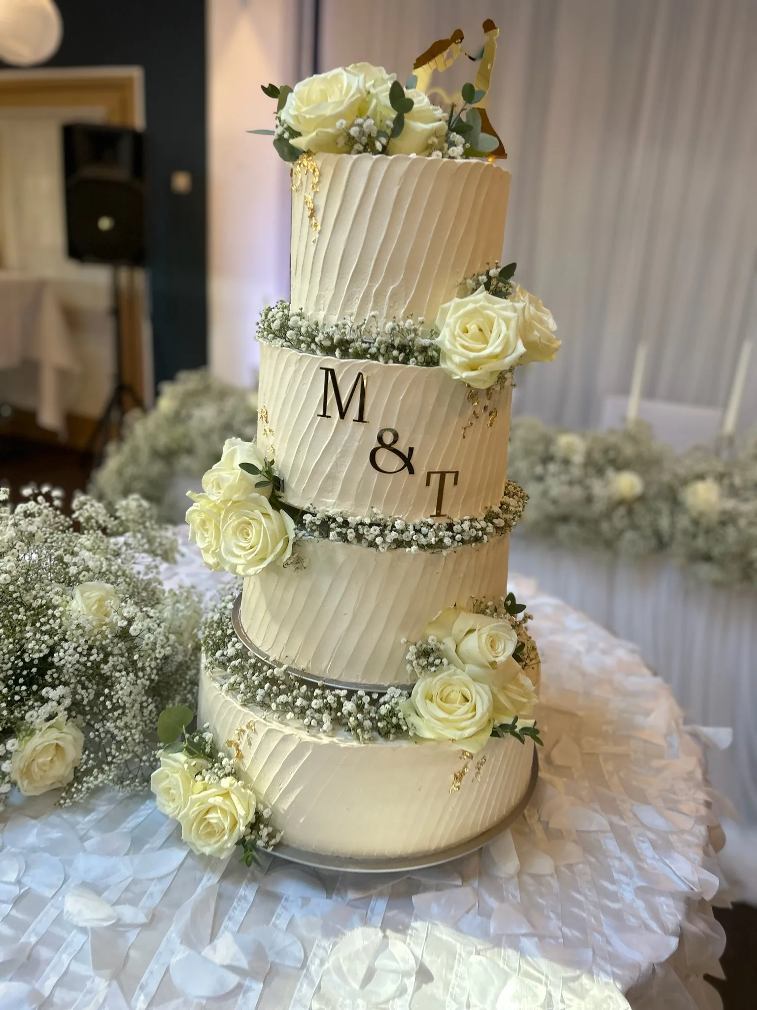 Vierstöckige Hochzeitstorte mit weißen Rosen und Initialen