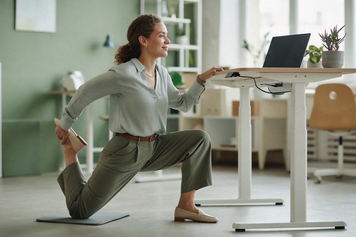 Office worker stretching her hip flexors beside a standing desk