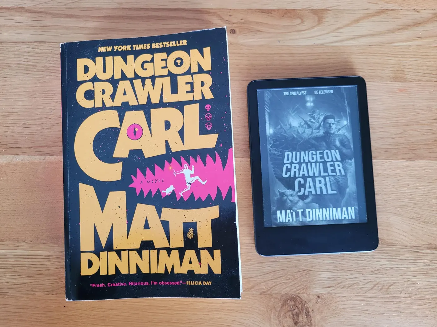 Dungeon Crawler Carl paperback next to 2022 Kindle for size comparison