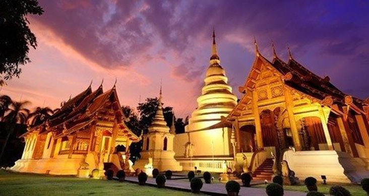 A golden-lit Thai temple complex at dusk