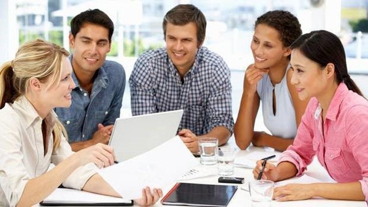 Interns and colleagues talking around a meeting table
