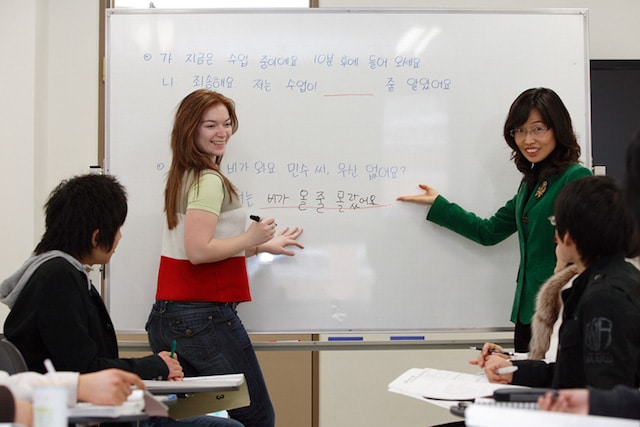 Instructor and student writing Korean on a whiteboard during a language class
