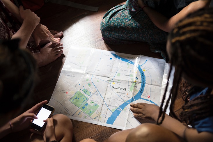 Friends planning a trip around a printed city map of Bangkok