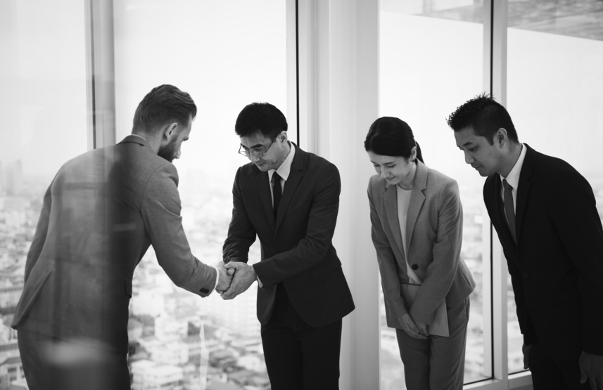 Business colleagues bowing and shaking hands in a city office
