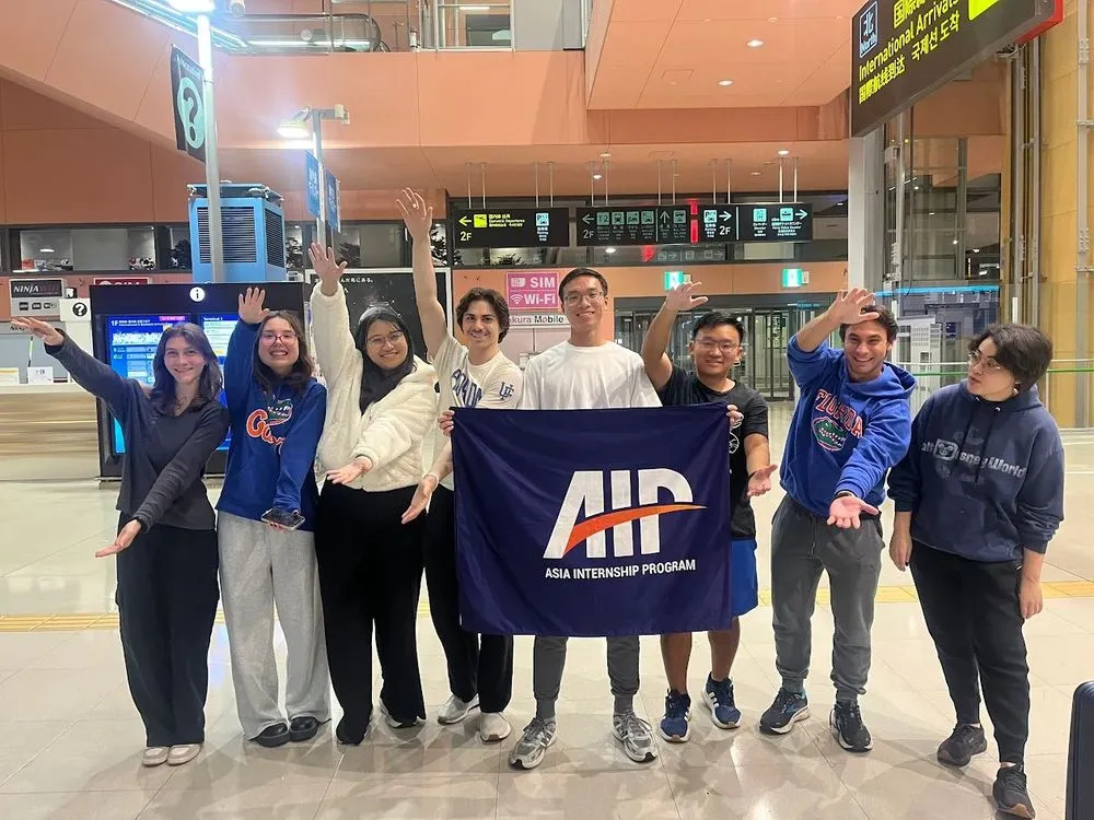 A university student group with the AIP banner at a station in Kyoto