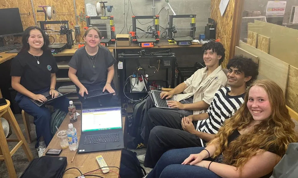 AIP interns working on laptops with their team in a maker lab