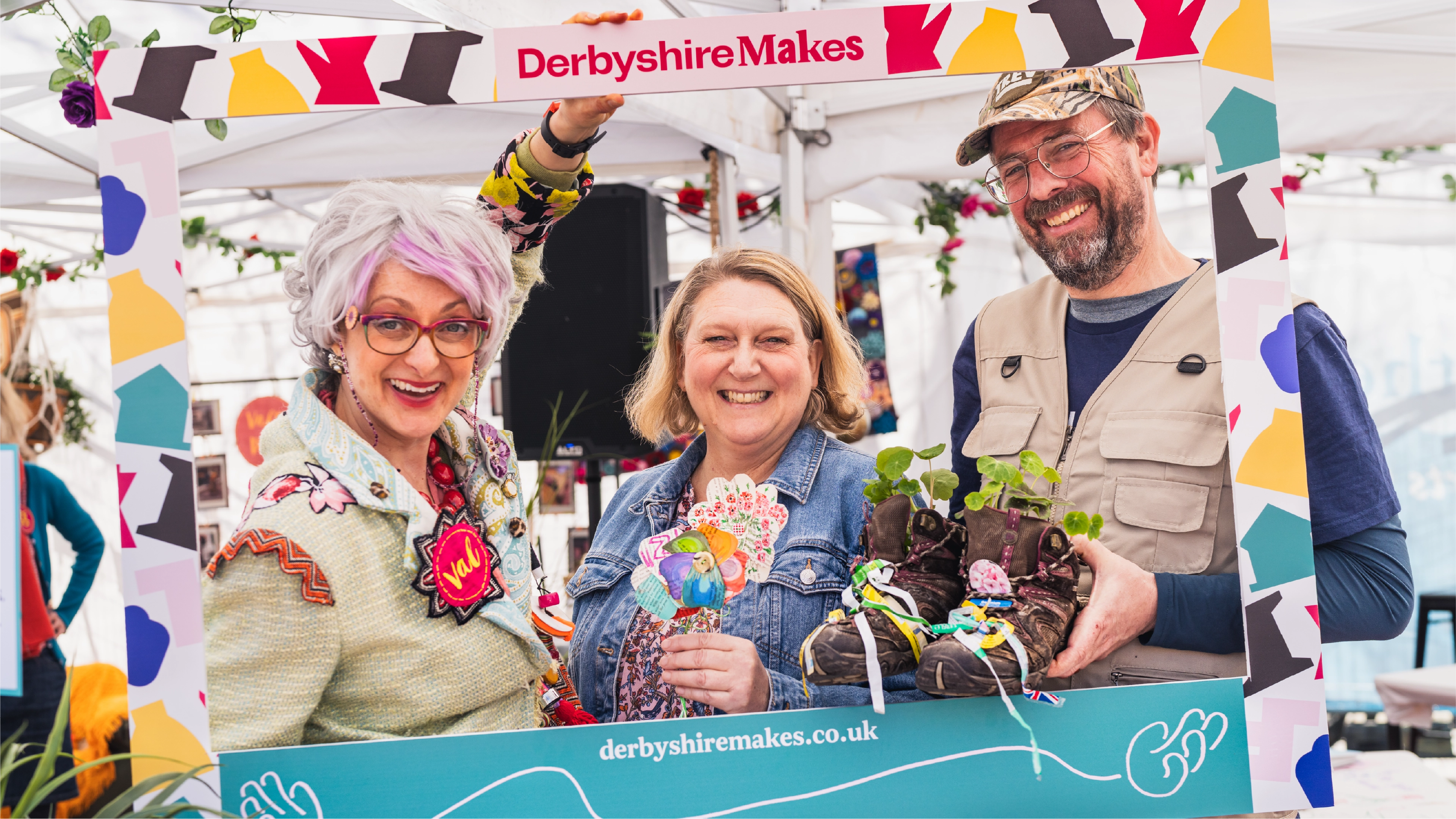 People holding a selfie frame created for Derbyshire Makes using the graphics from the brand identity created by Sanna Studio