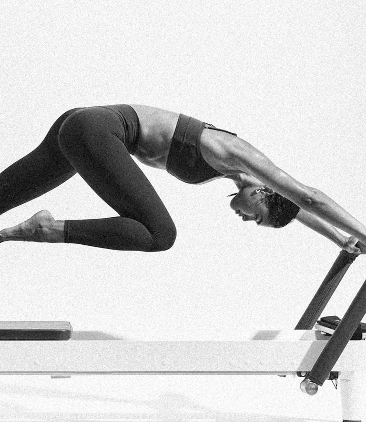 Woman stretching on a Pilates Reformer, in black and white