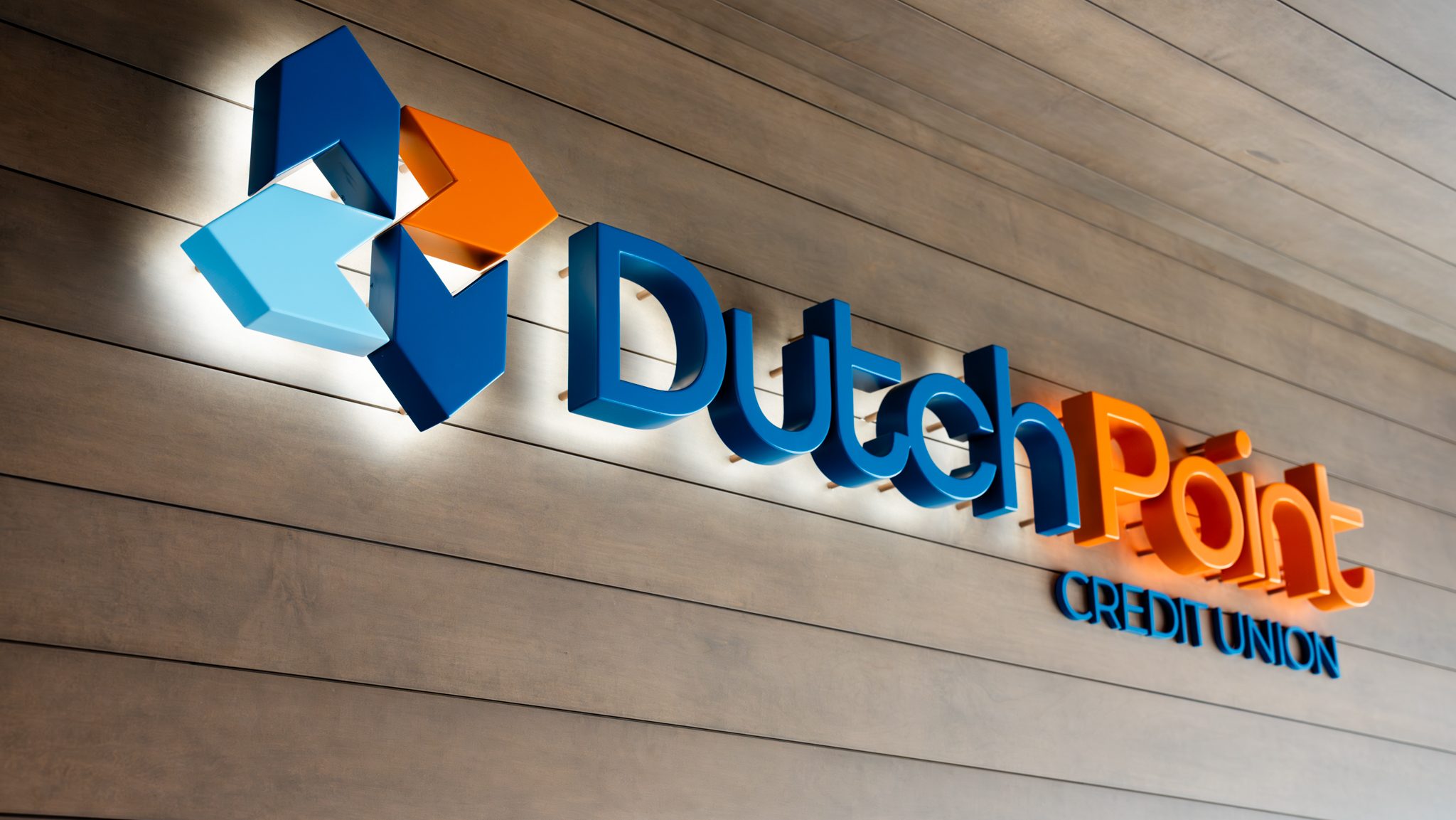 Illuminated Dutch Point Credit Union logo sign on a wood slat wall