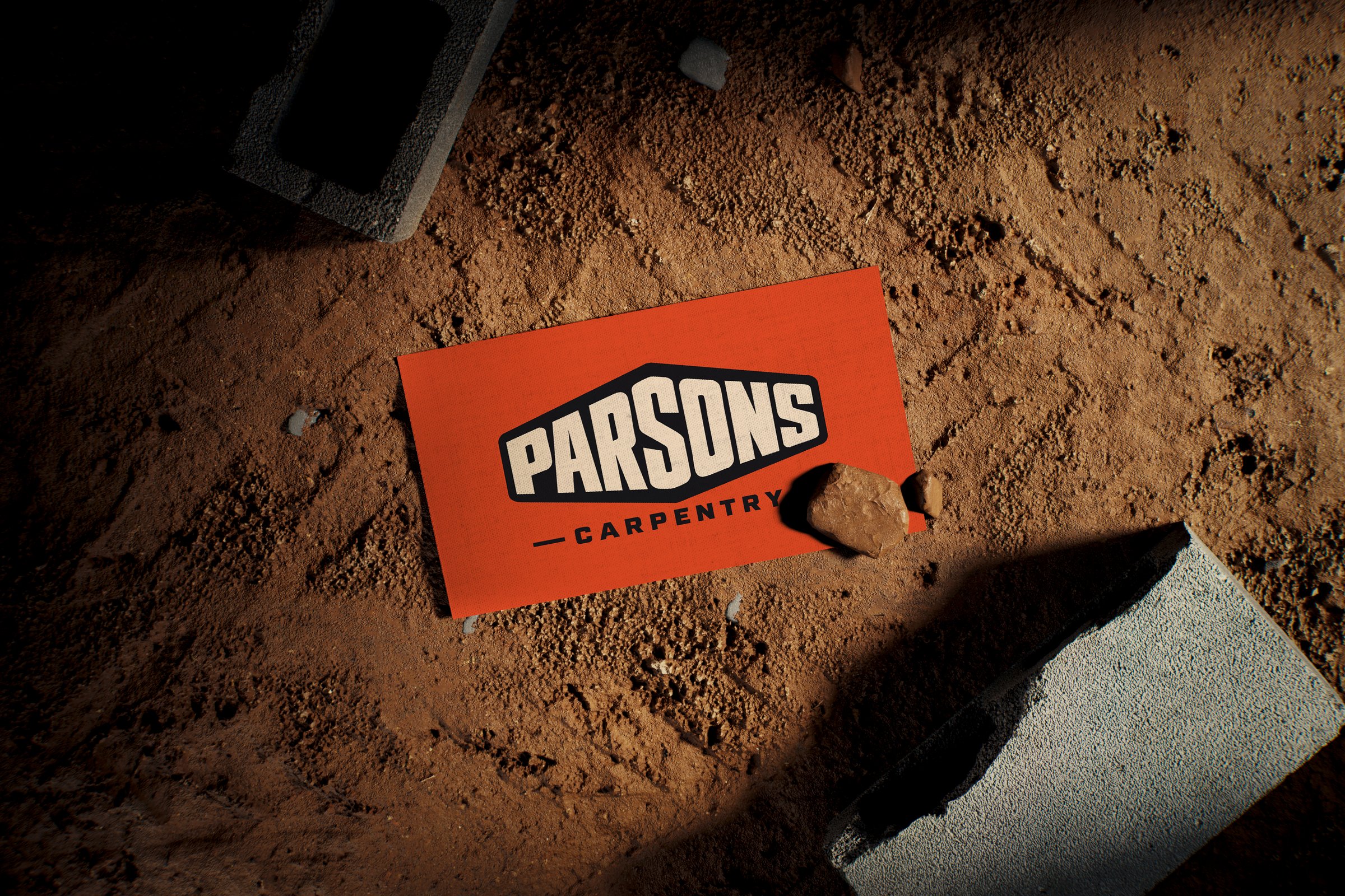 Orange Parsons Carpentry business card on a dirt jobsite