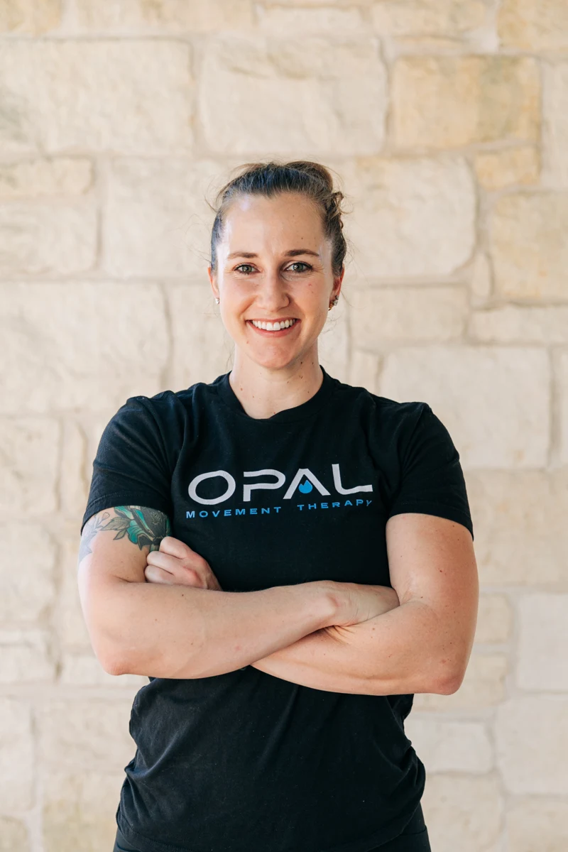 Morgan Rodriguez smiling with her arms crossed, wearing a black OPAL Movement Therapy shirt.