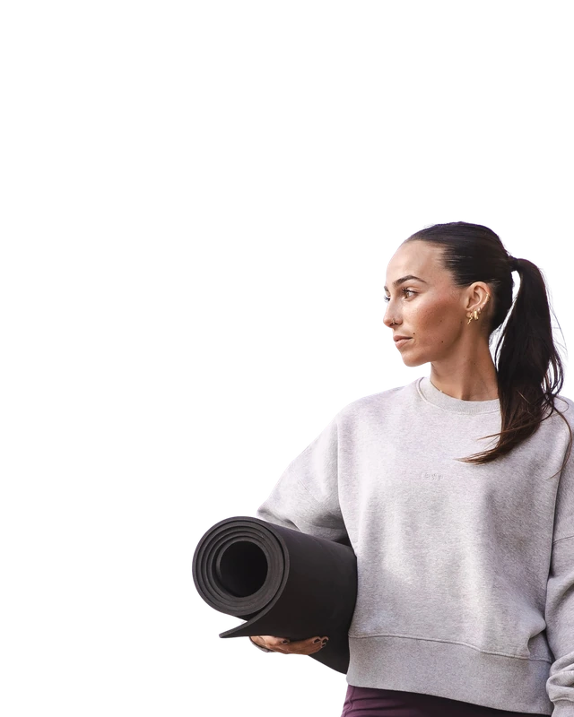 A woman carrying a rolled yoga mat.