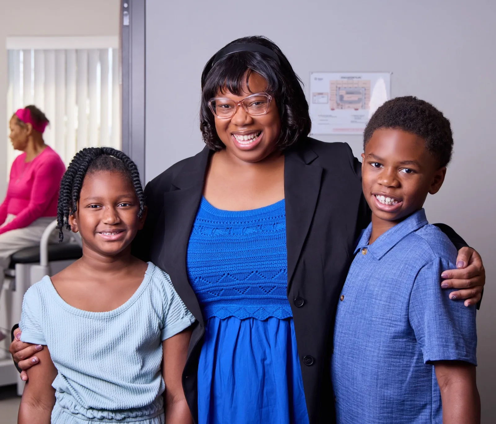 Kamilah Bywaters in a black blazer with a girl and a boy at her sides