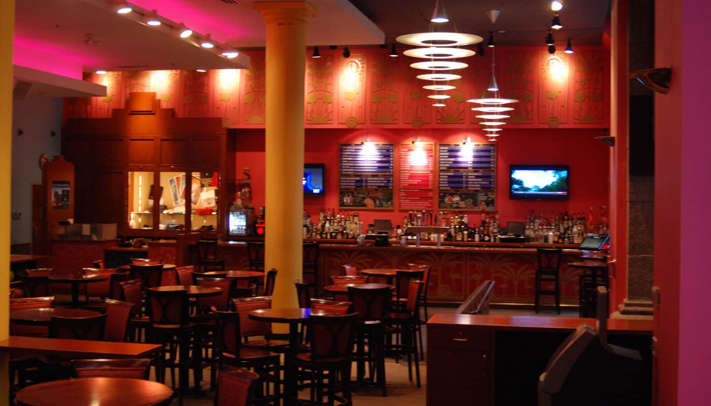 Main Room lounge tables with geometric chandeliers, red walls and the bar in the background
