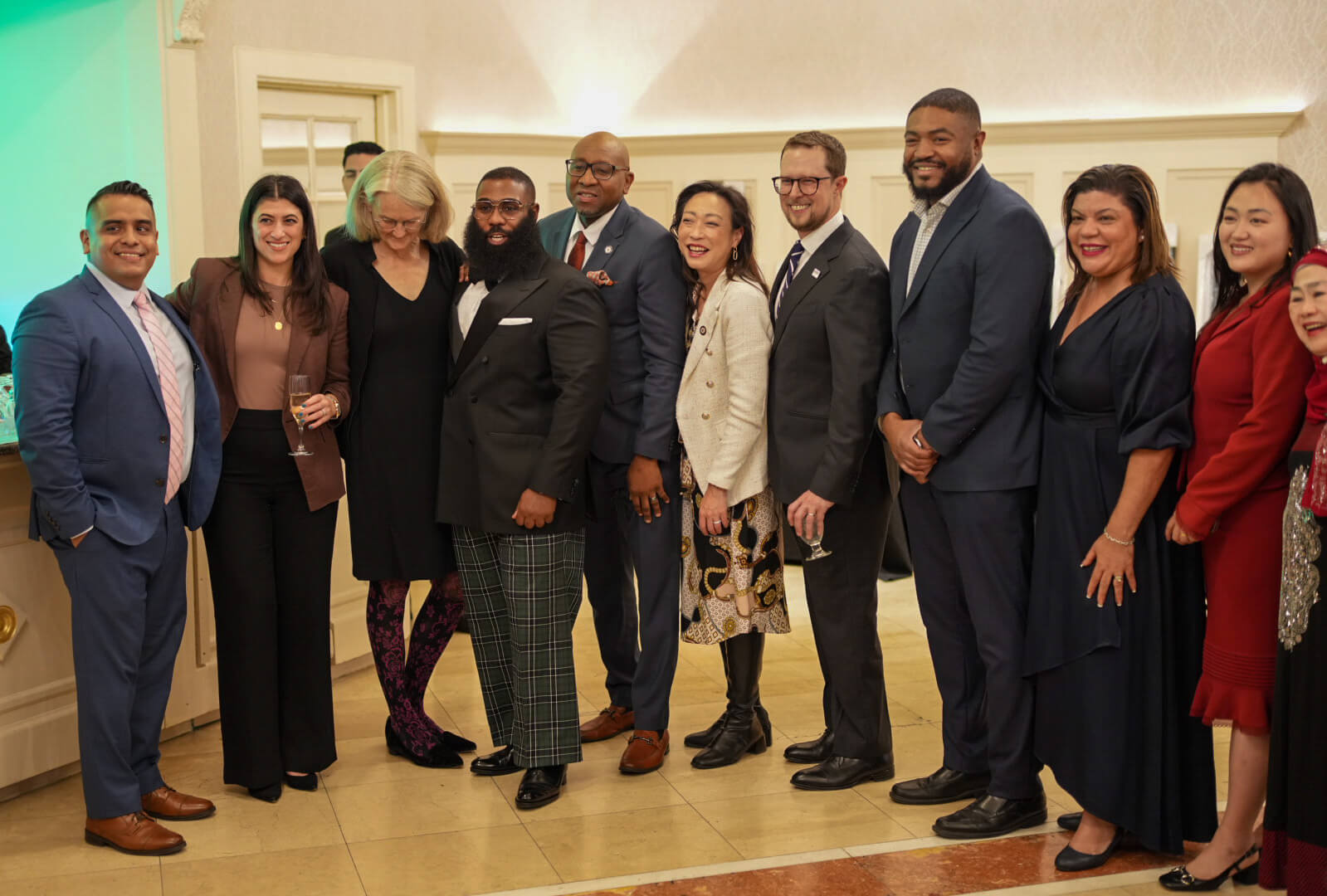 A large group of guests in formal attire gathers for a group photo in the ballroom.