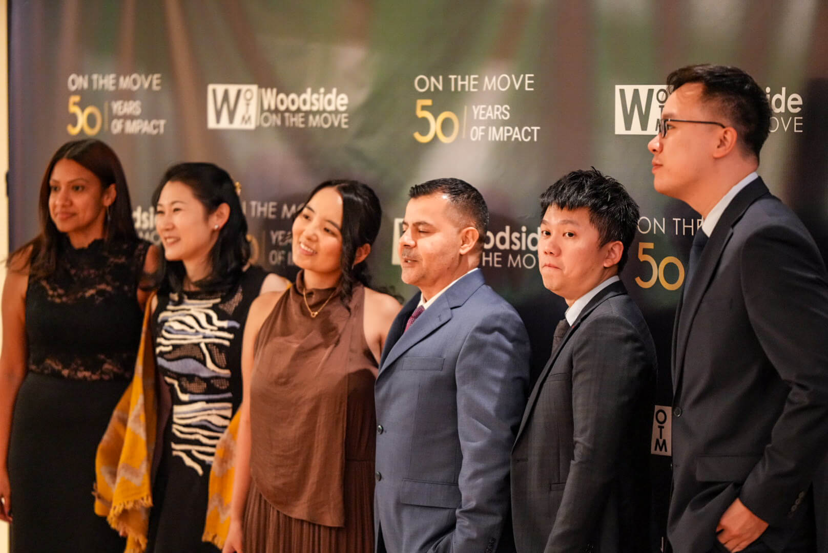 Guests pose together in front of the 50 Years of Impact backdrop.