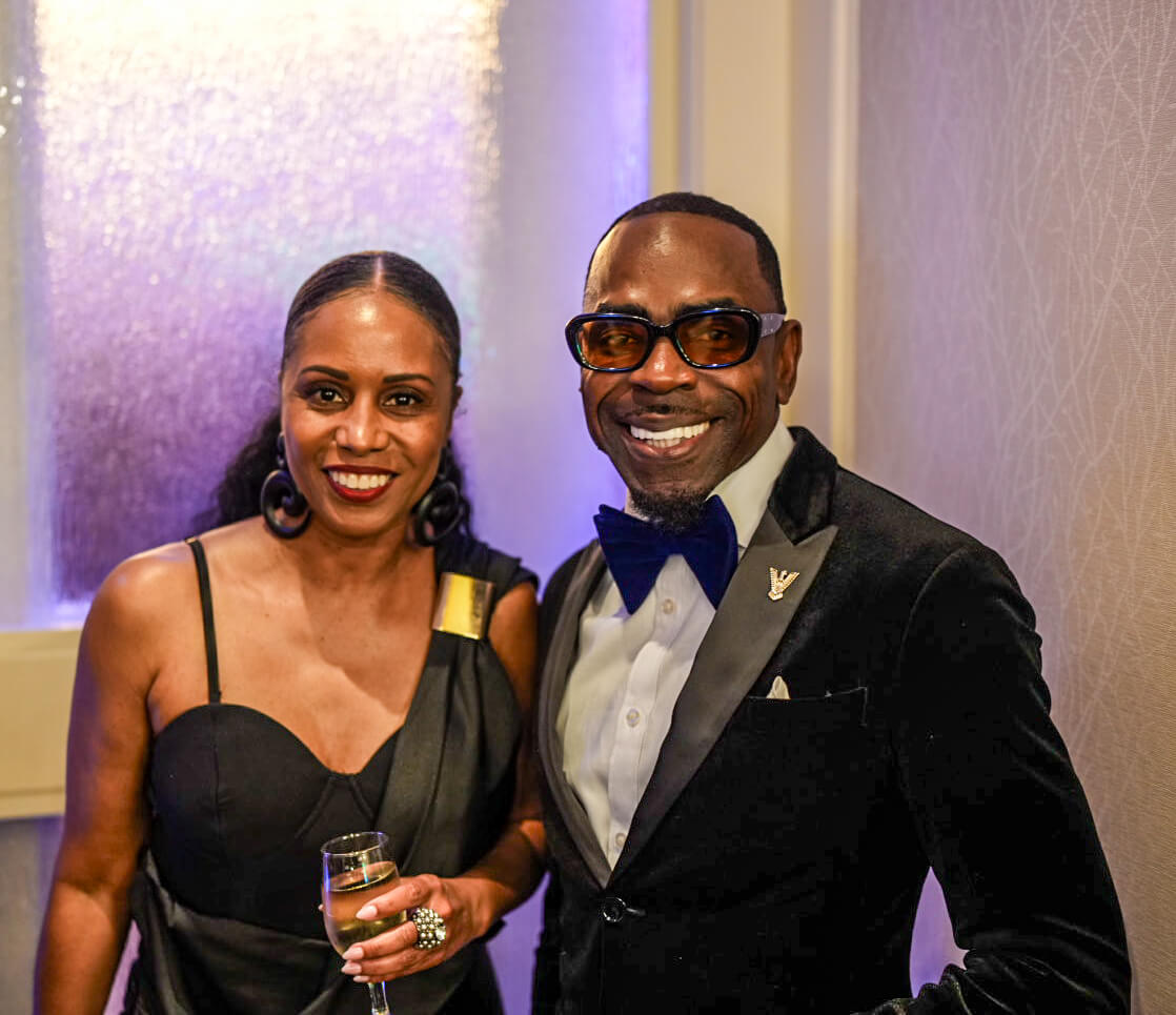 A woman and a man in a velvet tuxedo and bow tie smile for the camera.
