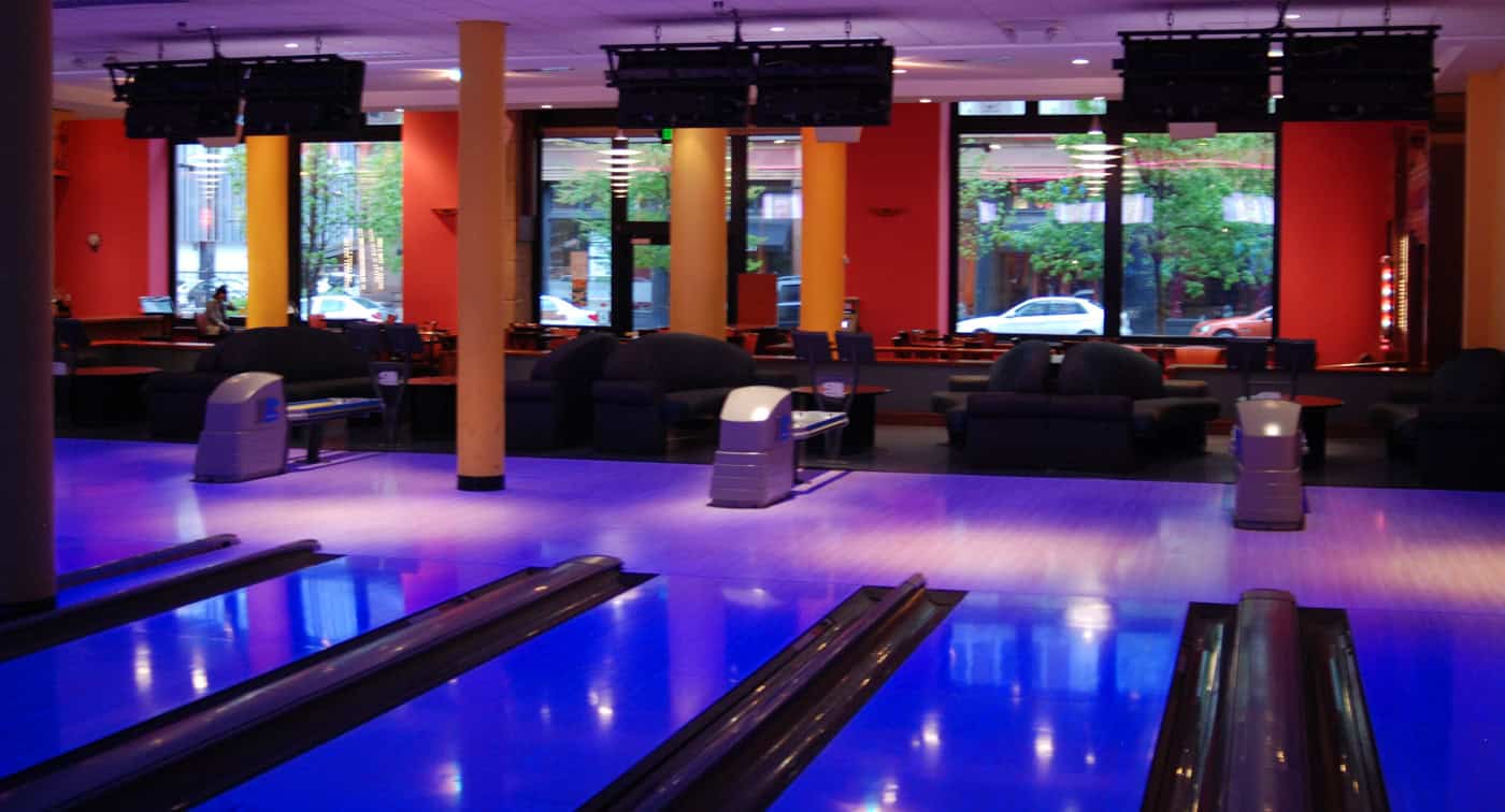 The ends of the bowling lanes with tall windows looking out onto Washington Avenue