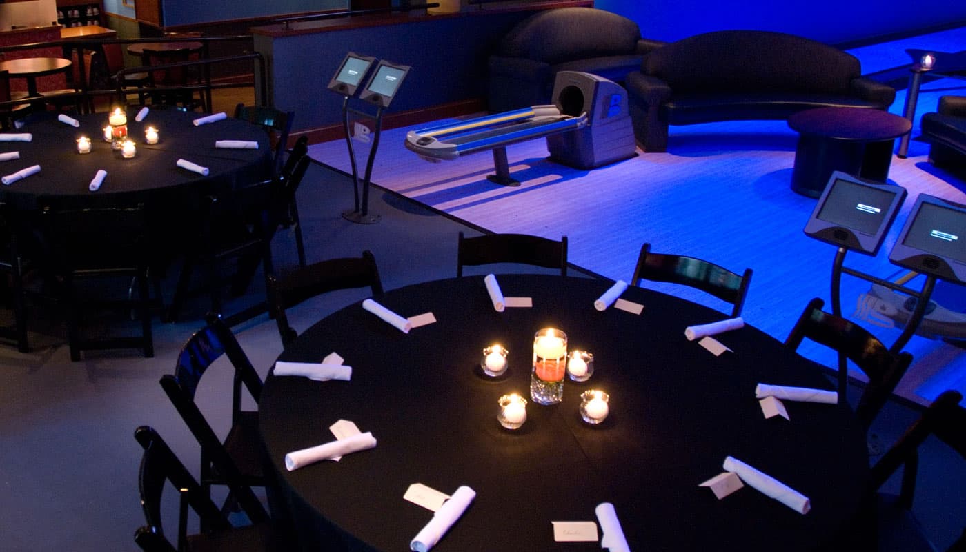 Round tables set with candles for a private event, lit in blue