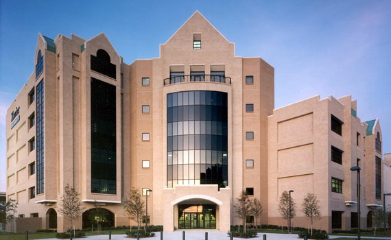 Xavier University Library. Modern multi-story building with beige stone facade and large vertical glass windows under a clear blue sky.