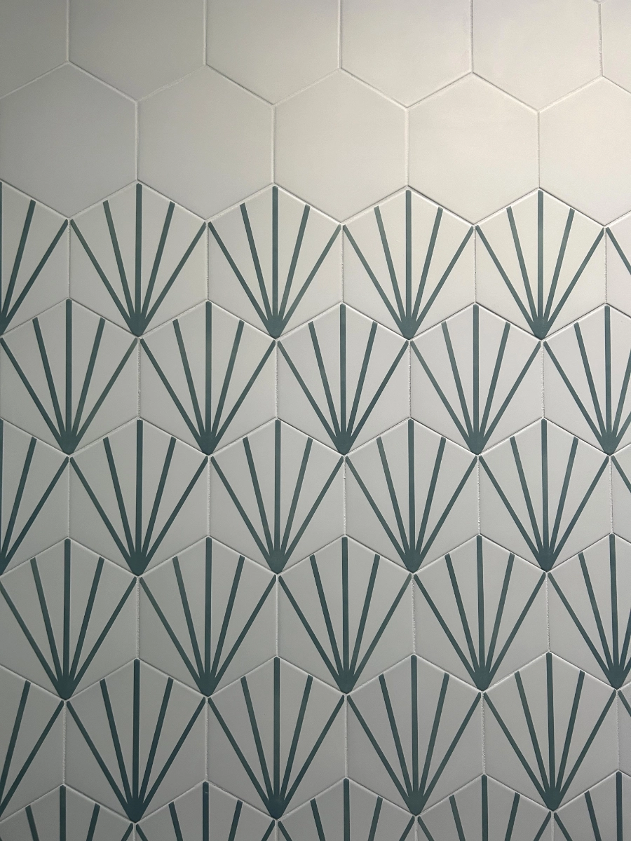 White hexagonal tile wall with a dark green geometric fan pattern on the bottom tiles.