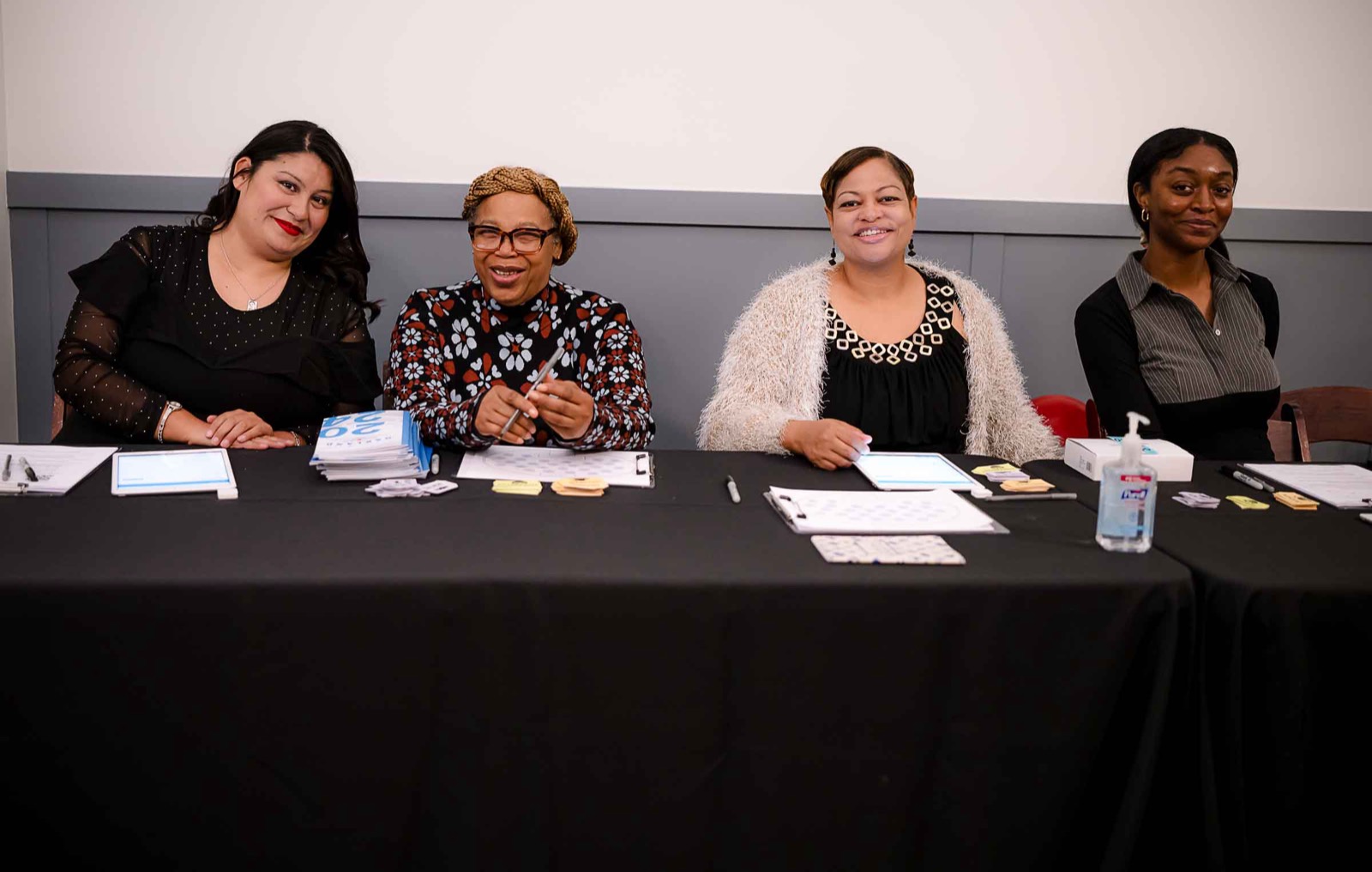 Four smiling Boys & Girls Clubs of Oakland team members seated at a registration table at an event