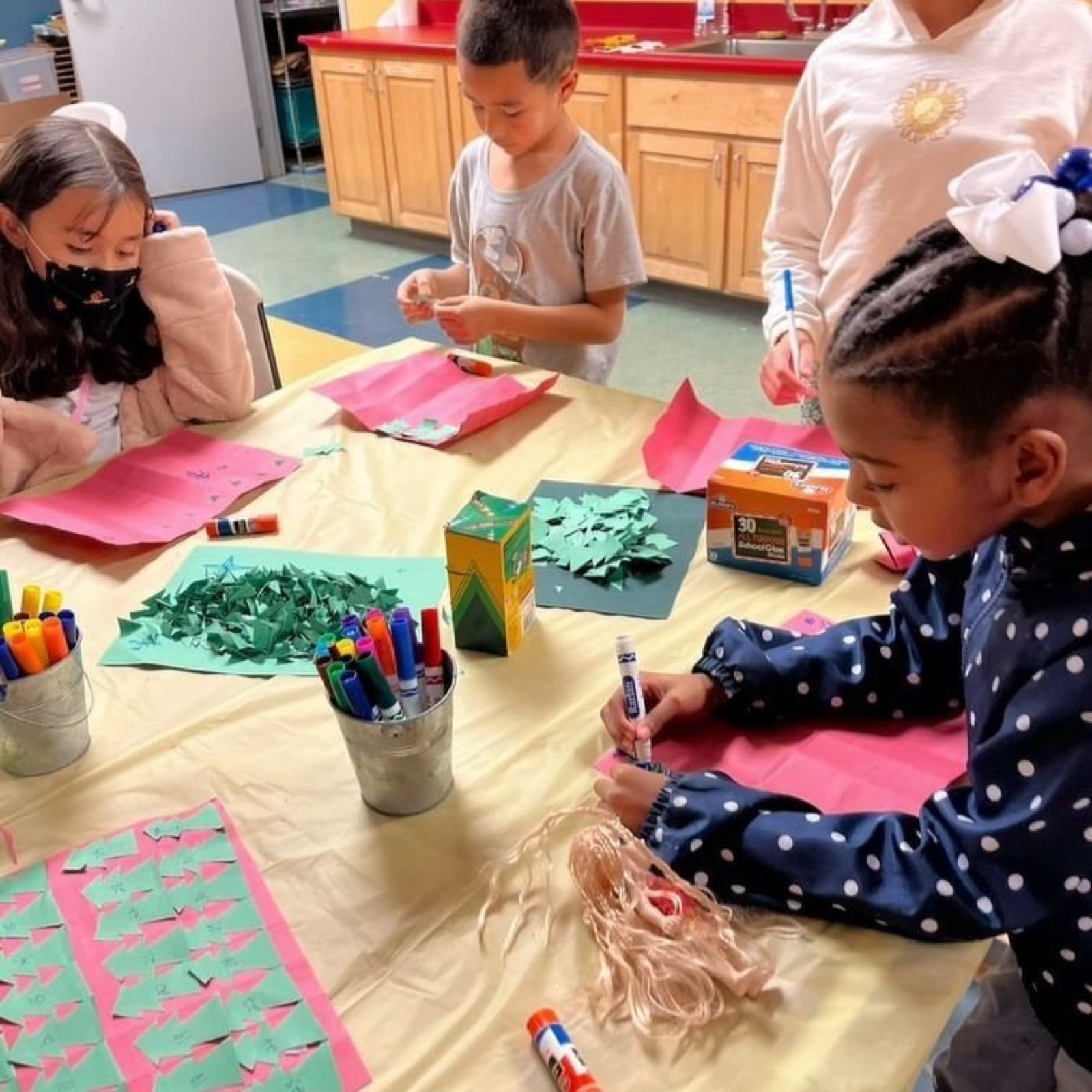 Children making paper crafts together at an arts table