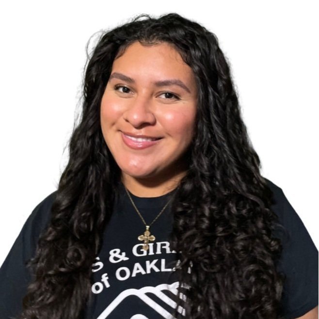Smiling young woman with long dark curly hair wearing a Boys & Girls Clubs of Oakland T-shirt