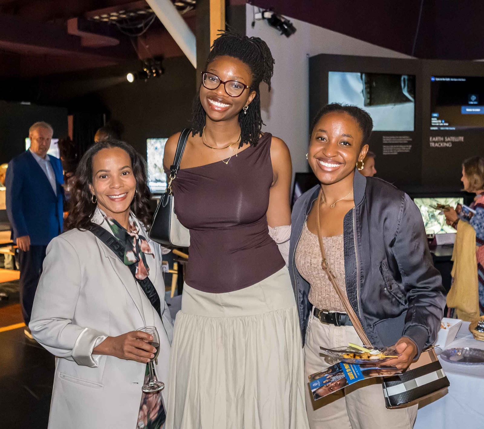 Three women smiling together at the gala reception in the science museum