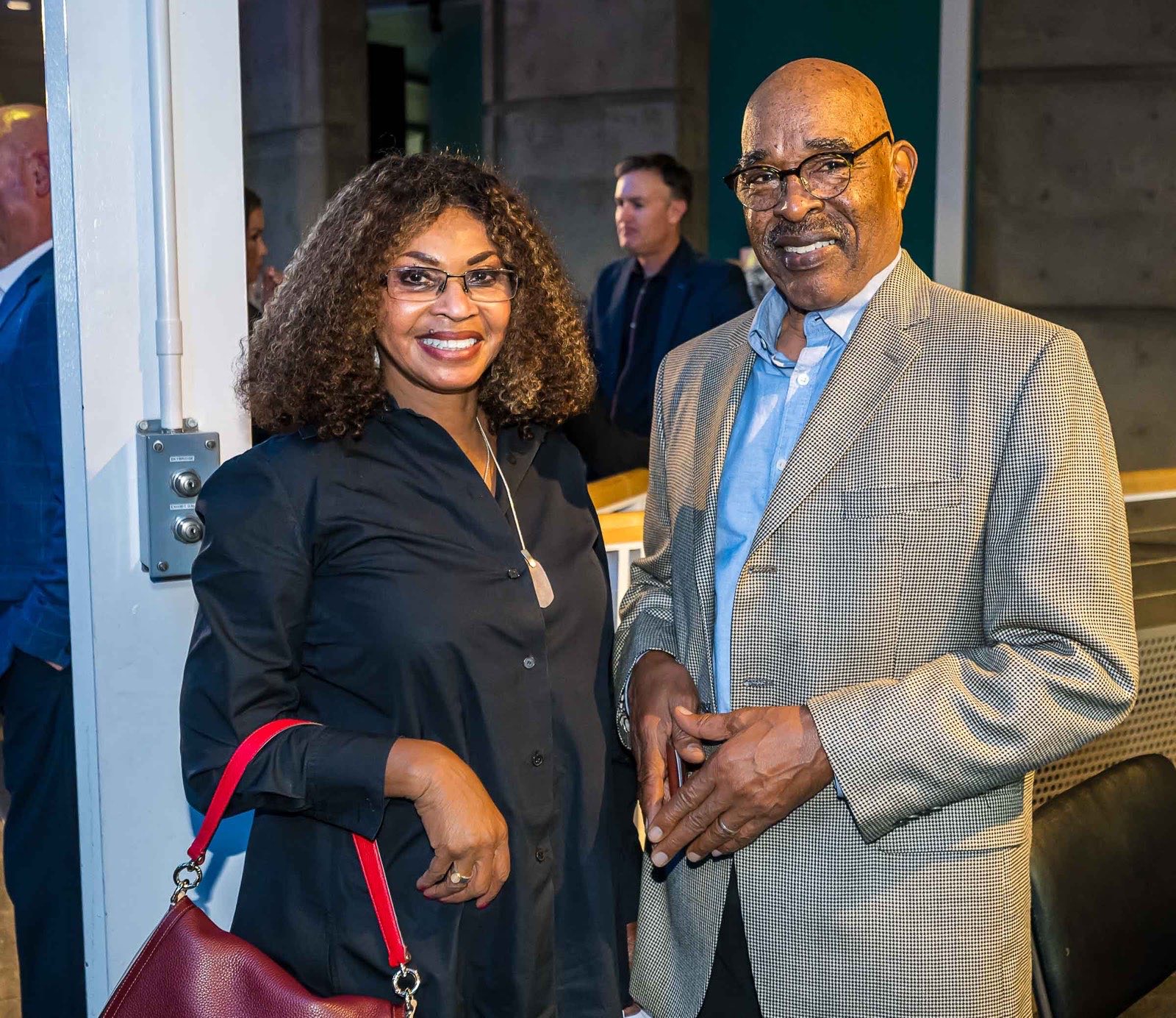 A woman in a black blouse and an older man in a gray blazer posing together at the gala