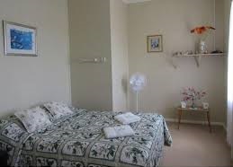 Bedroom with patterned bedspread and folded towels at Nimmitabel Motel