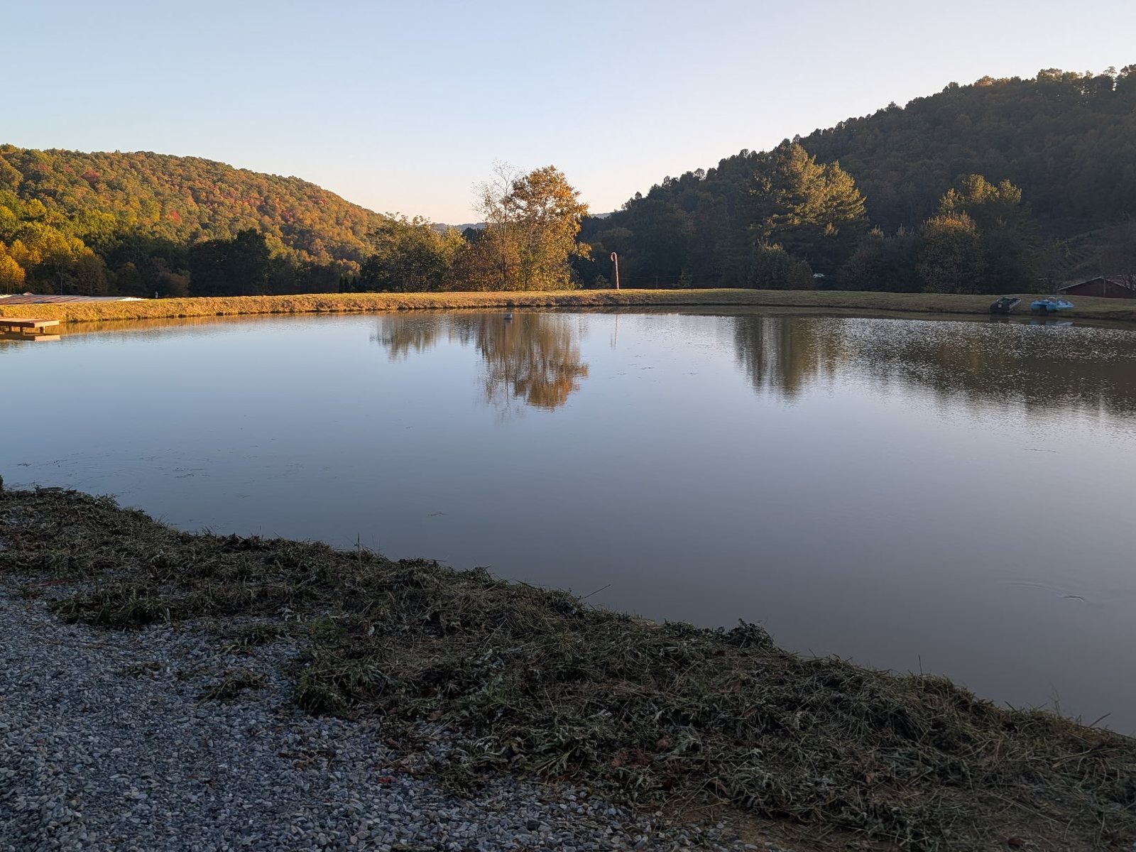 Finished mountain pond with graded banks and a dock, built by Western Carolina Earthworx