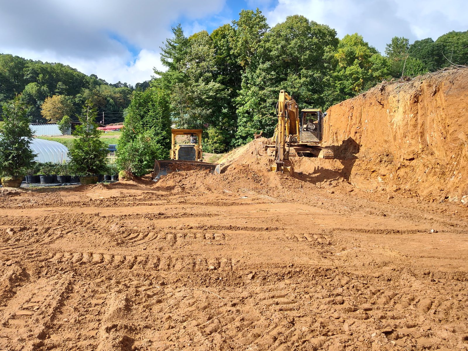 Excavator and dozer cutting a hillside building pad near Spruce Pine, NC