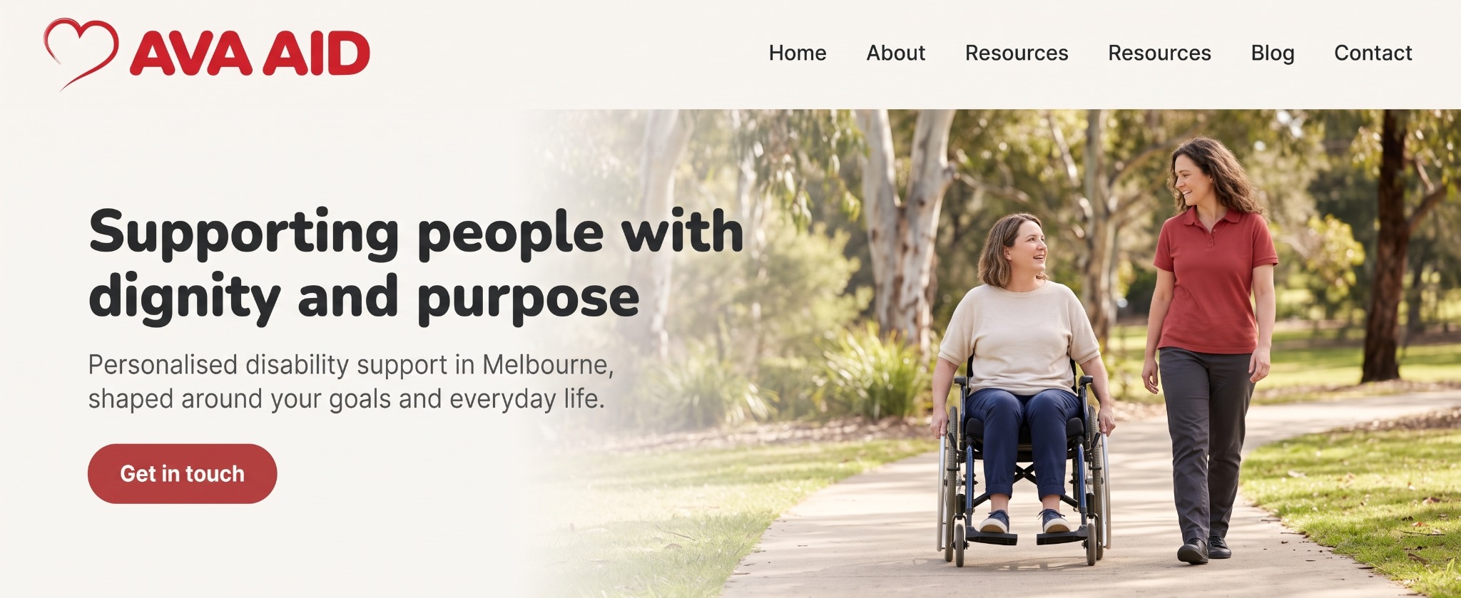 A woman using a wheelchair alongside a support worker on a park path.