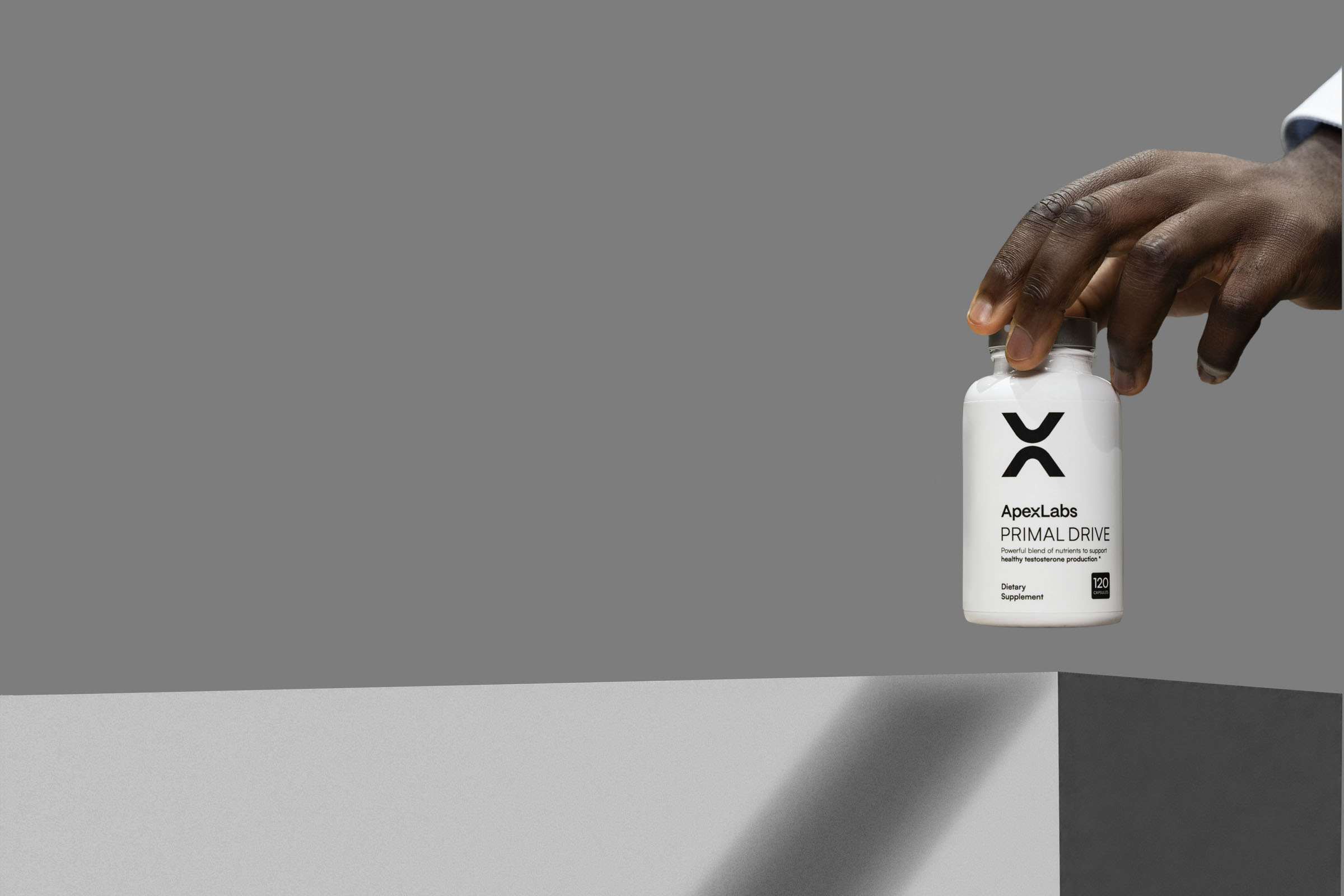 Hand holding an ApexLabs Primal Drive supplement bottle