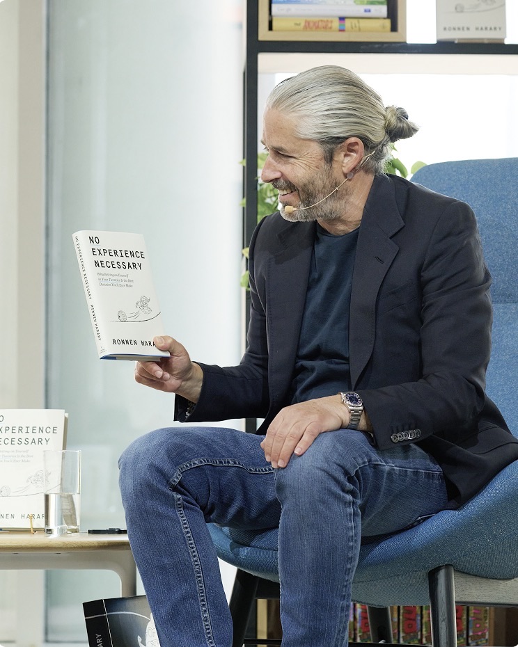Ronnen Harary smiling as he holds up his book No Experience Necessary