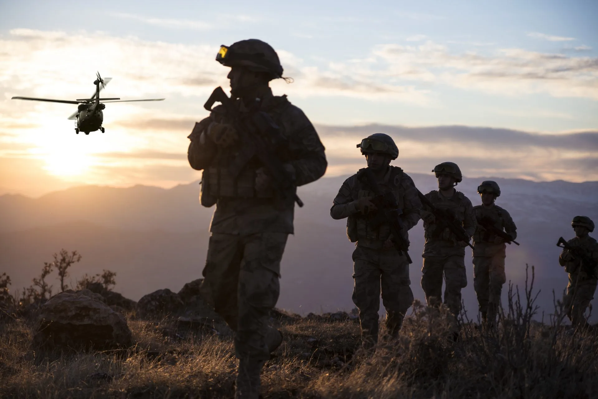 Soldiers with a helicopter silhouetted at sunset