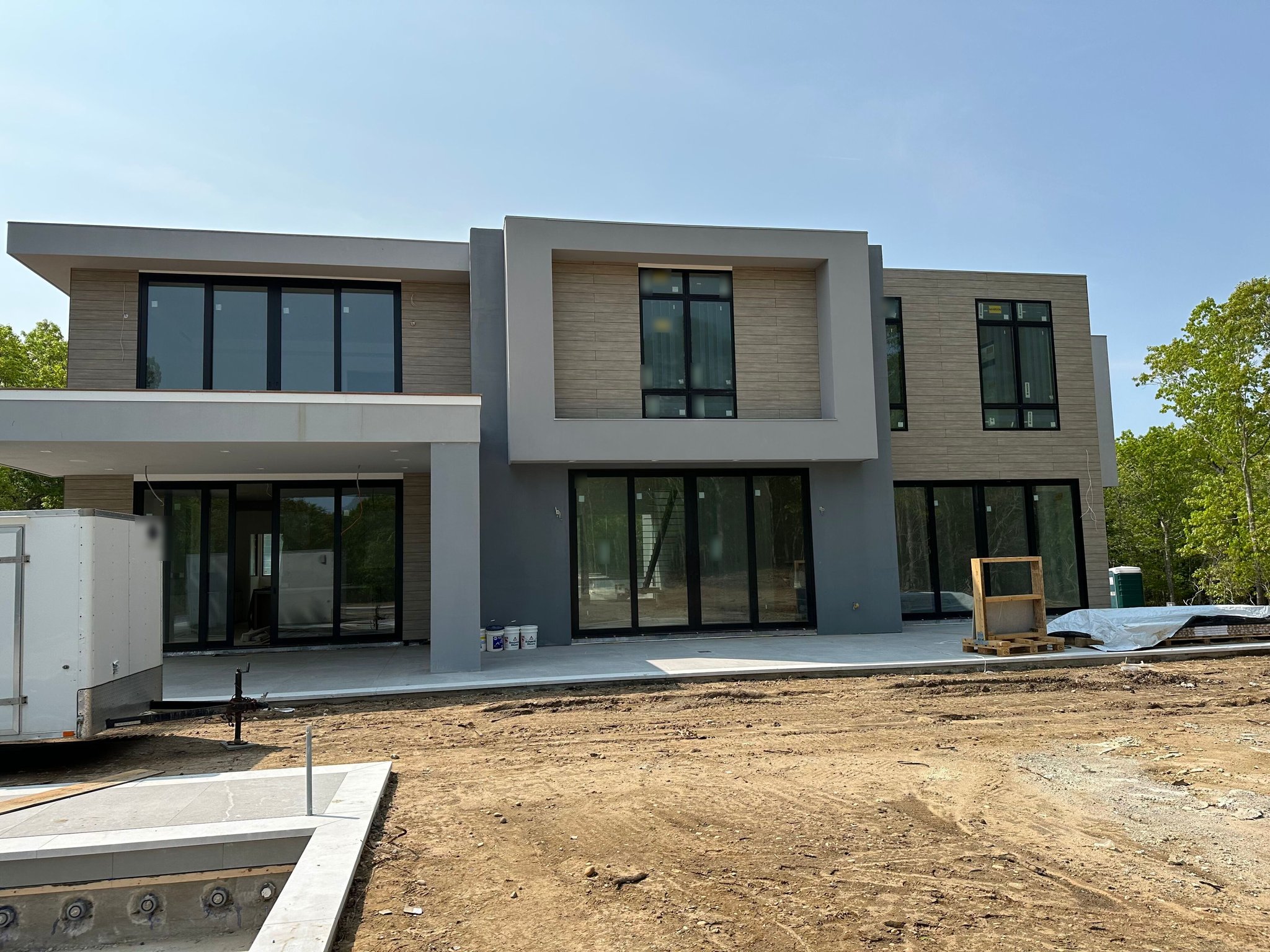 Rear elevation of a modern home with a single-brand window package and heavy black frames, during construction