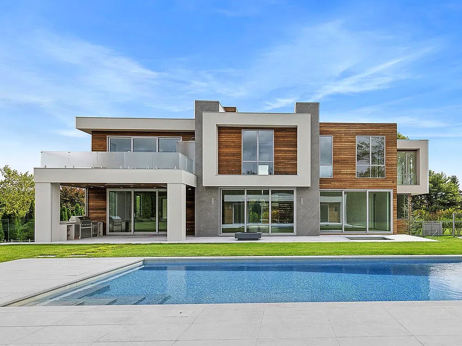 Rear elevation of a finished modern home with slim-frame glazing behind a pool