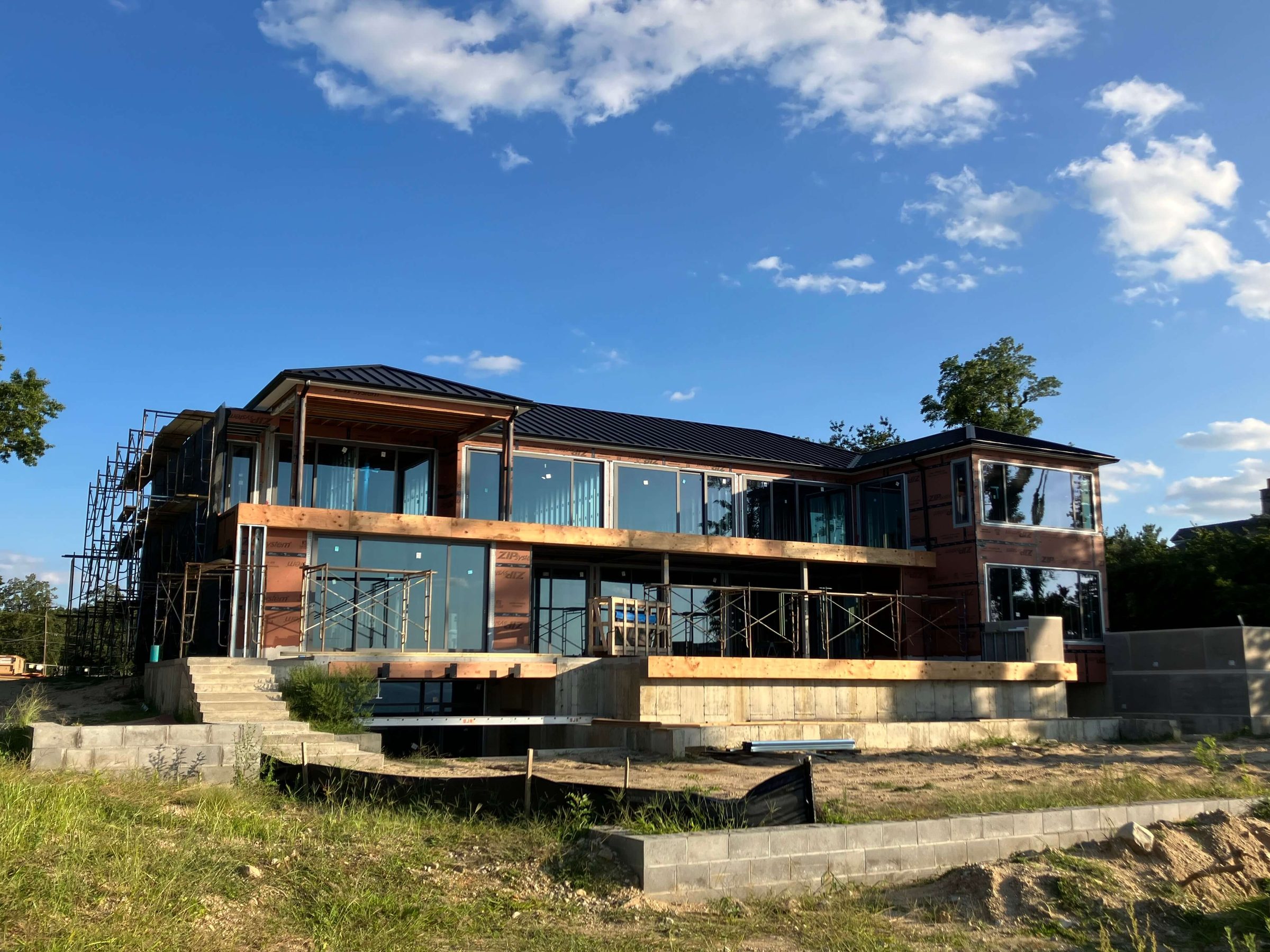 Two-story home in Sands Point, NY during construction, with large dark-framed Westline windows and sliding glass doors on both levels