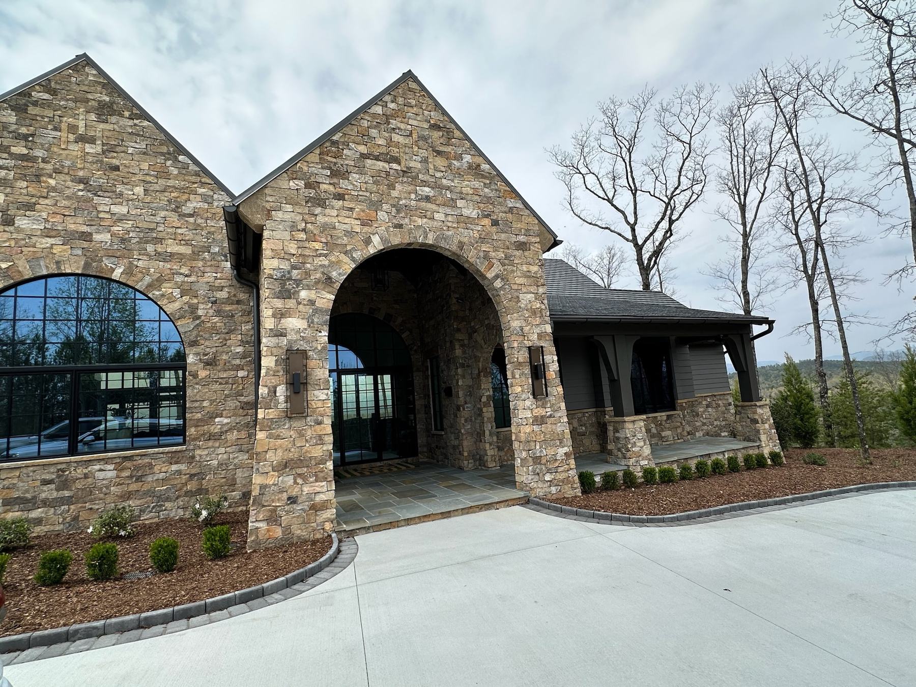 Stone entry arch and arched black-framed Westline window on a home at Lake Keowee, SC